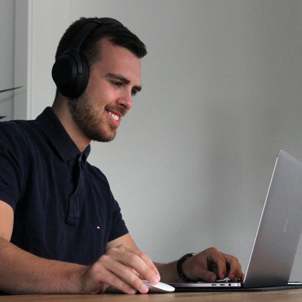 Smiling man on a virtual call through a laptop, using big headset