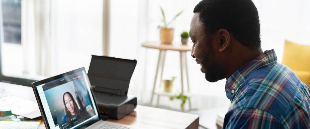 Smiling man on a virtual call through a laptop