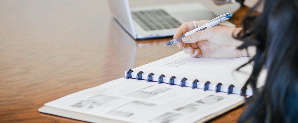 Zoom in on a women's hand writing in an agenda